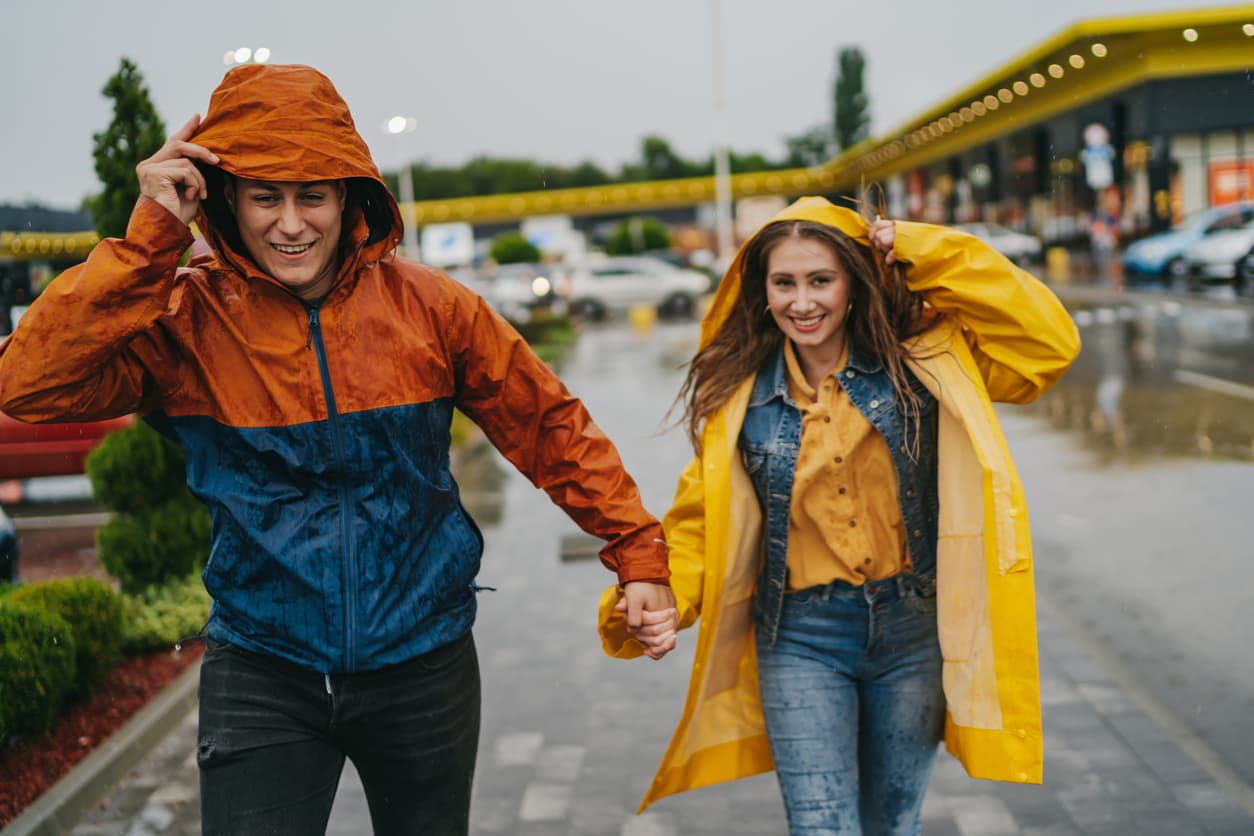 Cheerful young couple in a hurry, running in the city on a rainy day