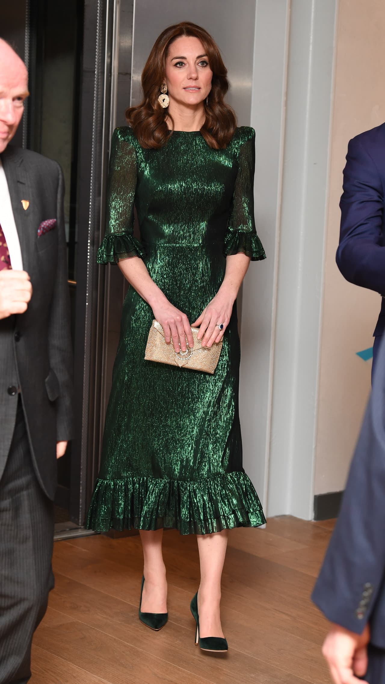 2020 - Una imagen antes de que el mundo explotara en covid y en la que podemos ver a Kate llegando a un evento en Dublín, Irlanda. El vestido que eligió, perfecto para una velada diplomática, es de un verde oscuro con brillos que la hacen resaltar sin robarse el protagonismo. Para complementaer, eligió unos zapatos de tacón bajo en color negro y, nuestros favoritos del outfit, unos aretes dorados.