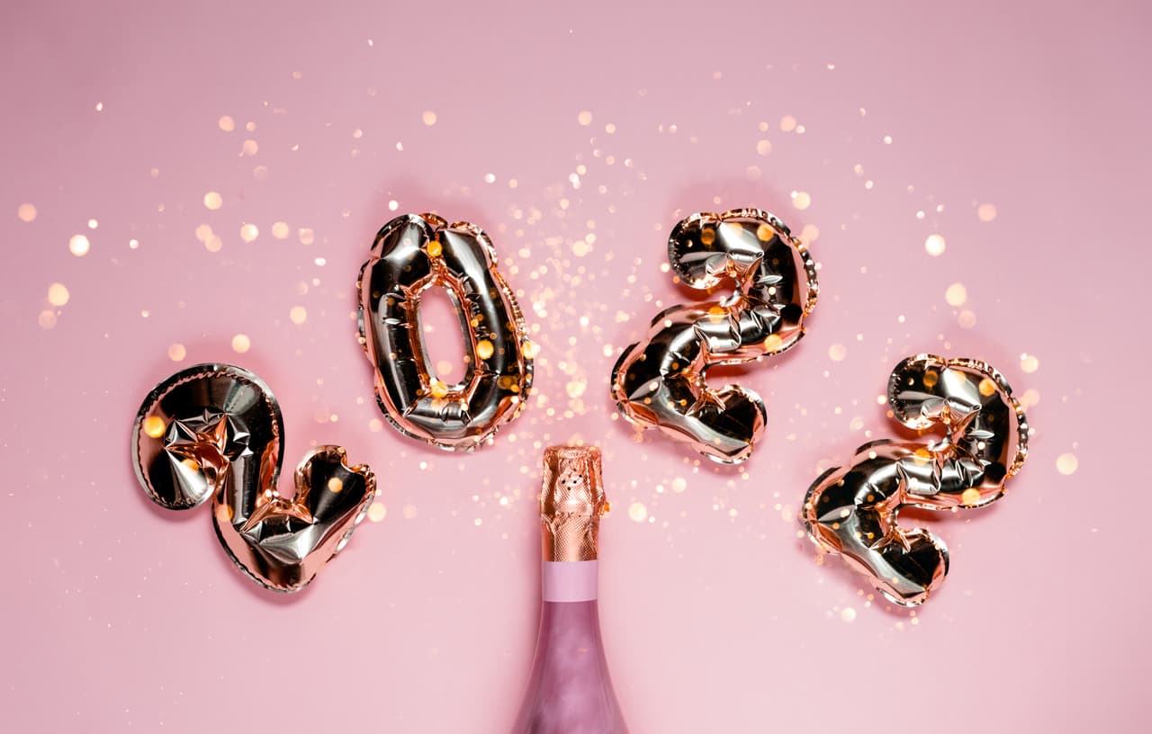2022 golden foil balloons with champagne bottle and confetti. Happy new year and festive concept. Top horizontal view copyspace.