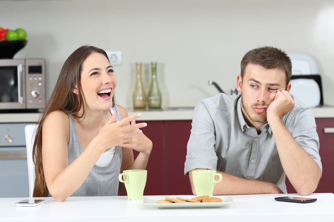 Bored husband hearing his wife talking during breakfast in the kitchen at home