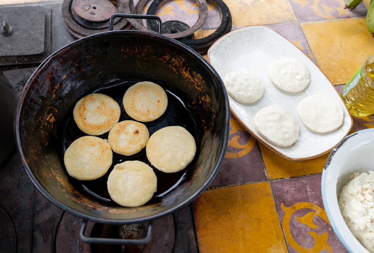 Close-up on a pan on the stove while making arepas in a rustic kitchen