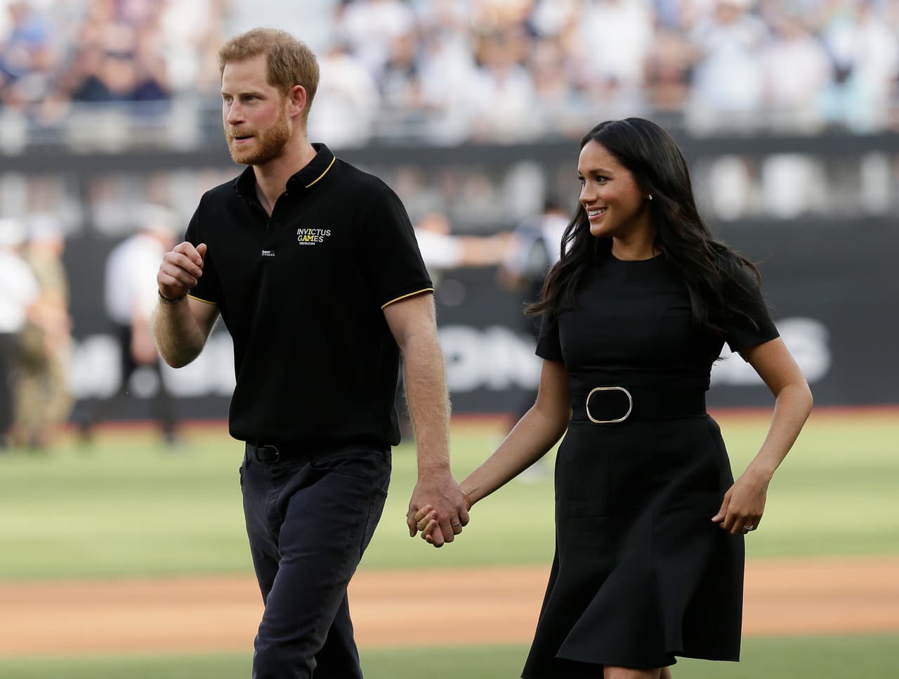 Britain's Prince Harry, left, and Meghan, Duchess of Sussex, walk off the field before a baseball game between the Boston Red Sox and the New York Yankees, Saturday, June 29, 2019, in London. Major League Baseball makes its European debut game today at London Stadium. (AP Photo/Tim Ireland)