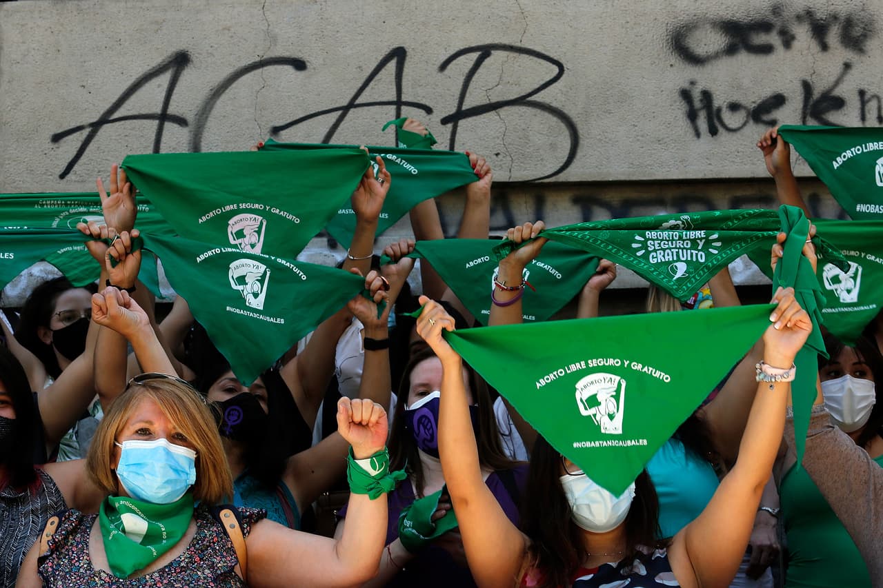 SANTIAGO, CHILE - JANUARY 13: Women of different feminist collectives hold up green handkerchiefs and shout slogans in front of La Moneda government palace during a pro-choice demonstration as deputies discuss abortion bill at La Moneda Palace on January 13, 2021 in Santiago, Chile. The comission of women and gender equality of the Chilean Congress will begin to discuss a law to decriminalize abortion until the 14th week of pregnancy. (Photo by Marcelo Hernandez/Getty Images)