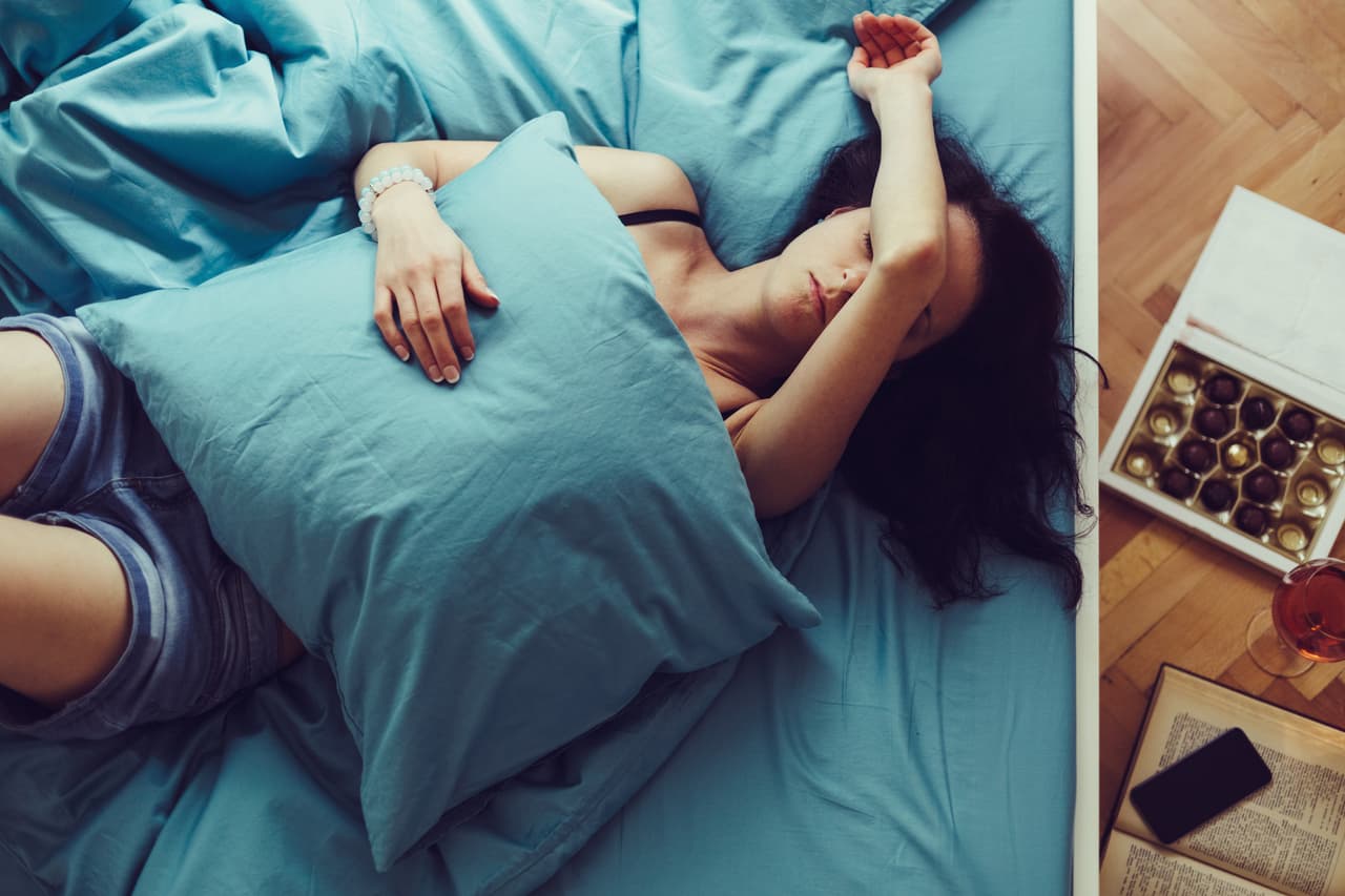 Depressed woman in bed with hand on forehead