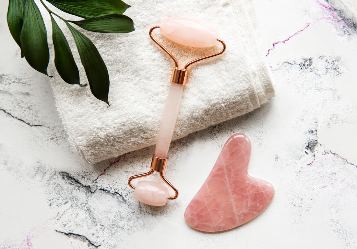 Jade face roller for beauty facial massage therapy with towel. Flat lay on marble background