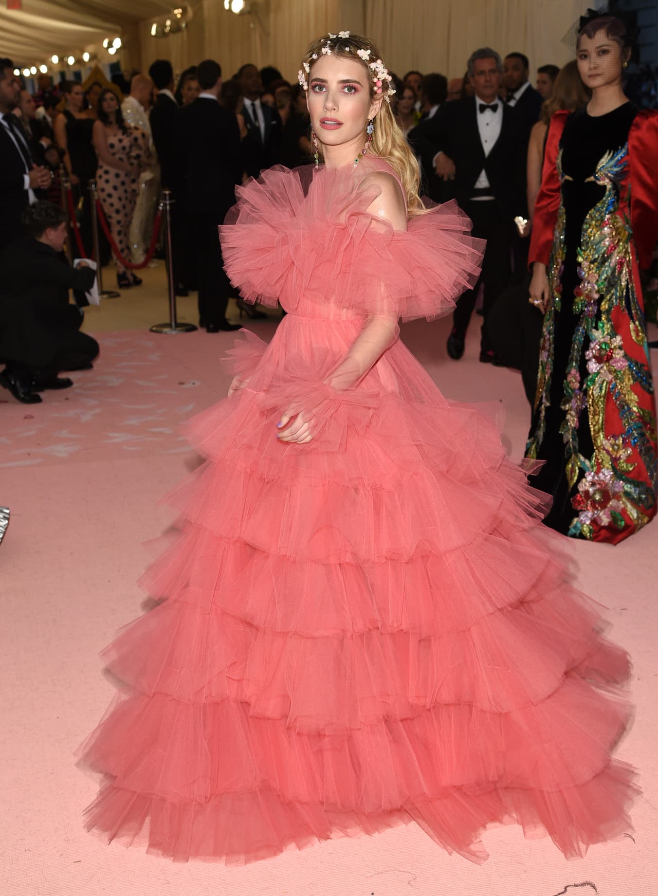 Emma Roberts usó un vestido rosa de tul con olanes y una delicada corona de flores como accesorio.
