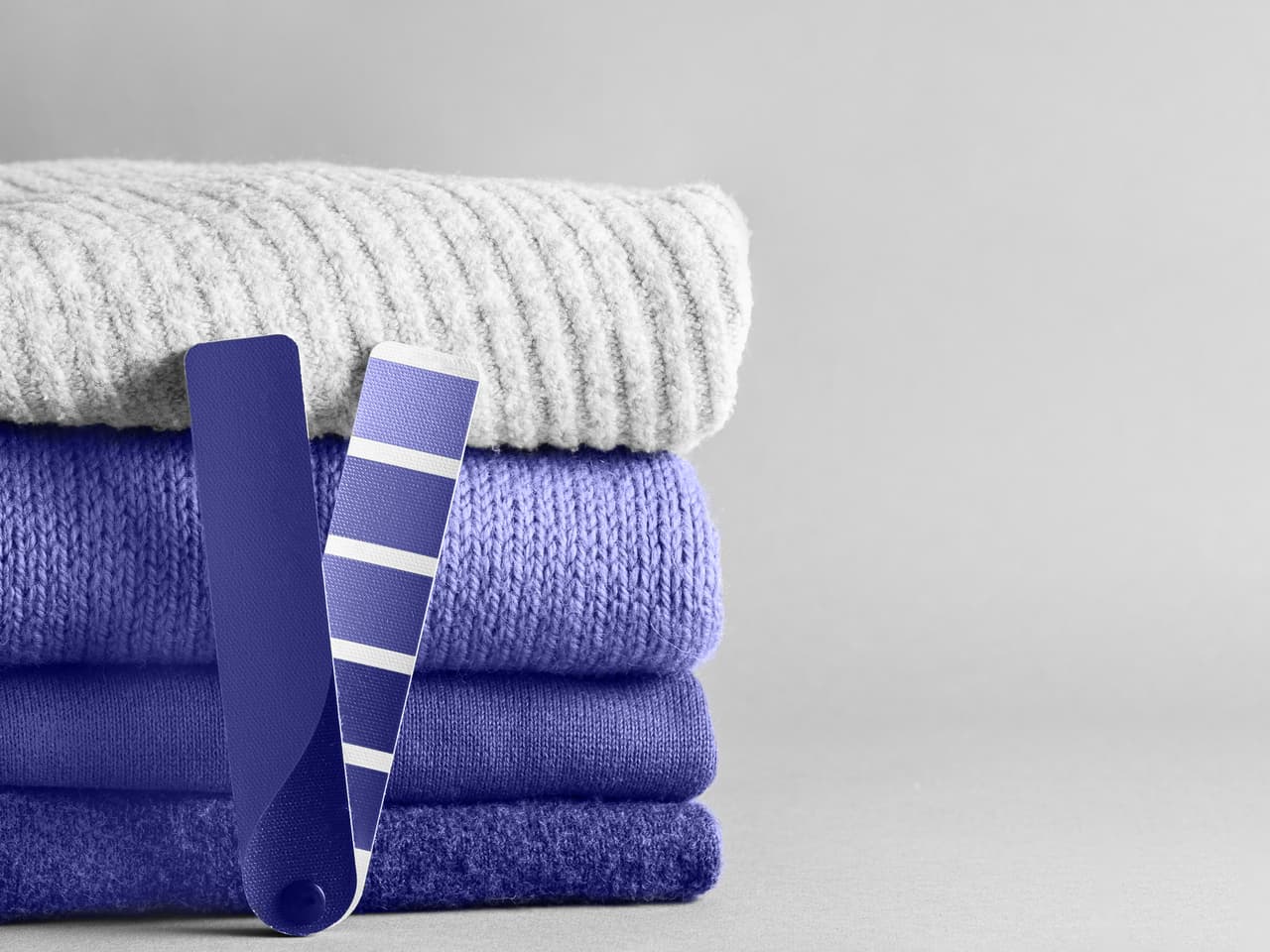 Stack of sweaters and color fun palette in violet color of 2020 year very peri. Demonstrating color of 2022 year very peri for fashion and clothing industry. Copy space