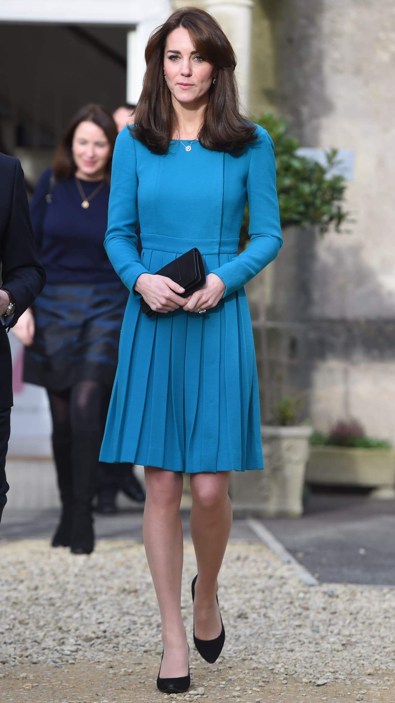 2015 - Desde el inicio Kate ha sido fiel exponente de que "menos es más", lo cual intenta aplicar en todos sus outfits ¡y logra hacerlo a la perfección! Aquí podemos ver a la duquesa con un vestido azul con falda pliegada, manga larga y un discreto collar plateado que le da un gran toque al look. Como siempre, su bolso está combinado con sus zapatos y en su totalidad, hace que se vea como un digno miembro de la realeza.