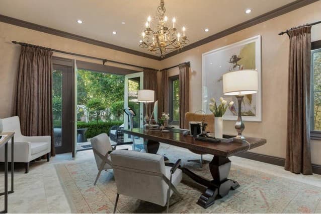 El gran estudio es, sin duda, un lugar muy espacioso, donde definitivamente todos quisiéramos hacer home office. Tiene unas cortinas color marrón, que combinan con el color de los muebles café oscuro, y el techo alto deja entrar la brisa por los ventanales.