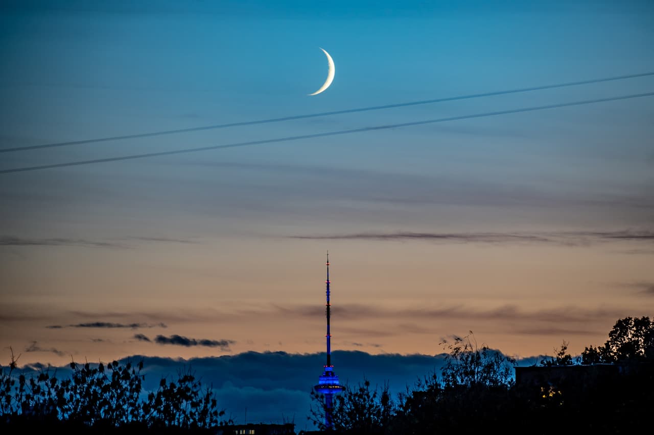 Beautiful orange and blue sunset with new moon over the city and Vilnius TV tower, Lithuania