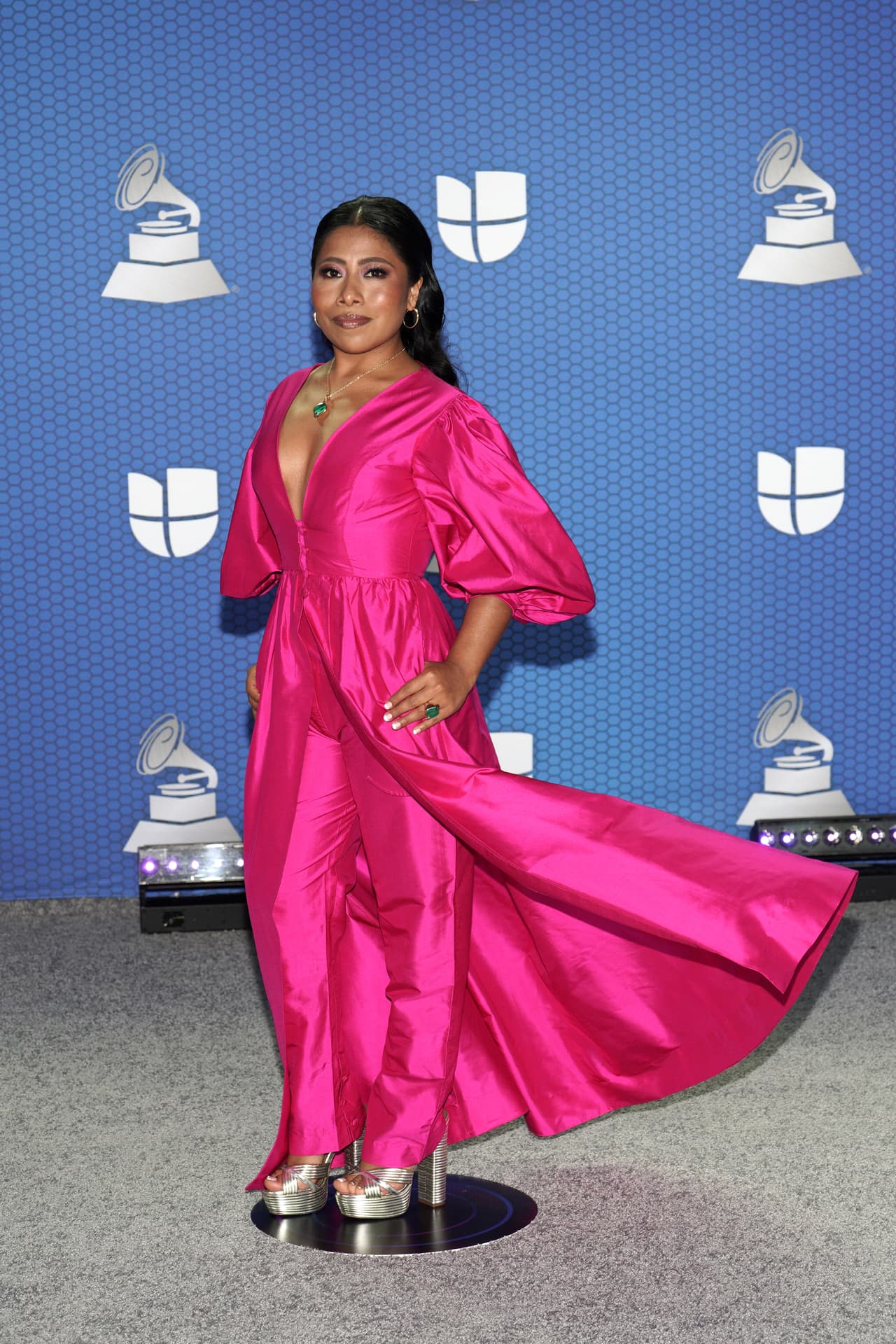 Durante su paso en la alfombra roja, Yalitza Aparicio dio una lección de cómo llevar uno de los colores más representativos de México. La oaxaqueña usó un traje con capa y pantalón por debajo de la marca brasileña, 
<b>Helo Rocha;</b> es un conjunto que consiste en un top con mangas abullonadas, escote pronunciado y botones a la cintura, mientras por debajo se asoma un pantalón de tubo en el mismo color.