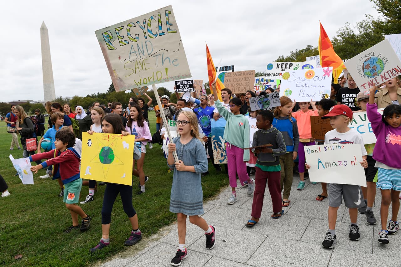 FILE - In this Friday, Sept. 13, 2019 file photo, young climate activists march with signs during a rally near the White House in Washington. At left is the Washington Monument. In late September 2019, there will be climate strikes, climate summits, climate debates, a dire climate science report, climate pledges by countries and businesses, promises of climate financial help and more between now and next Friday. There will even be a bit of climate poetry, film and music. (AP Photo/Susan Walsh)
