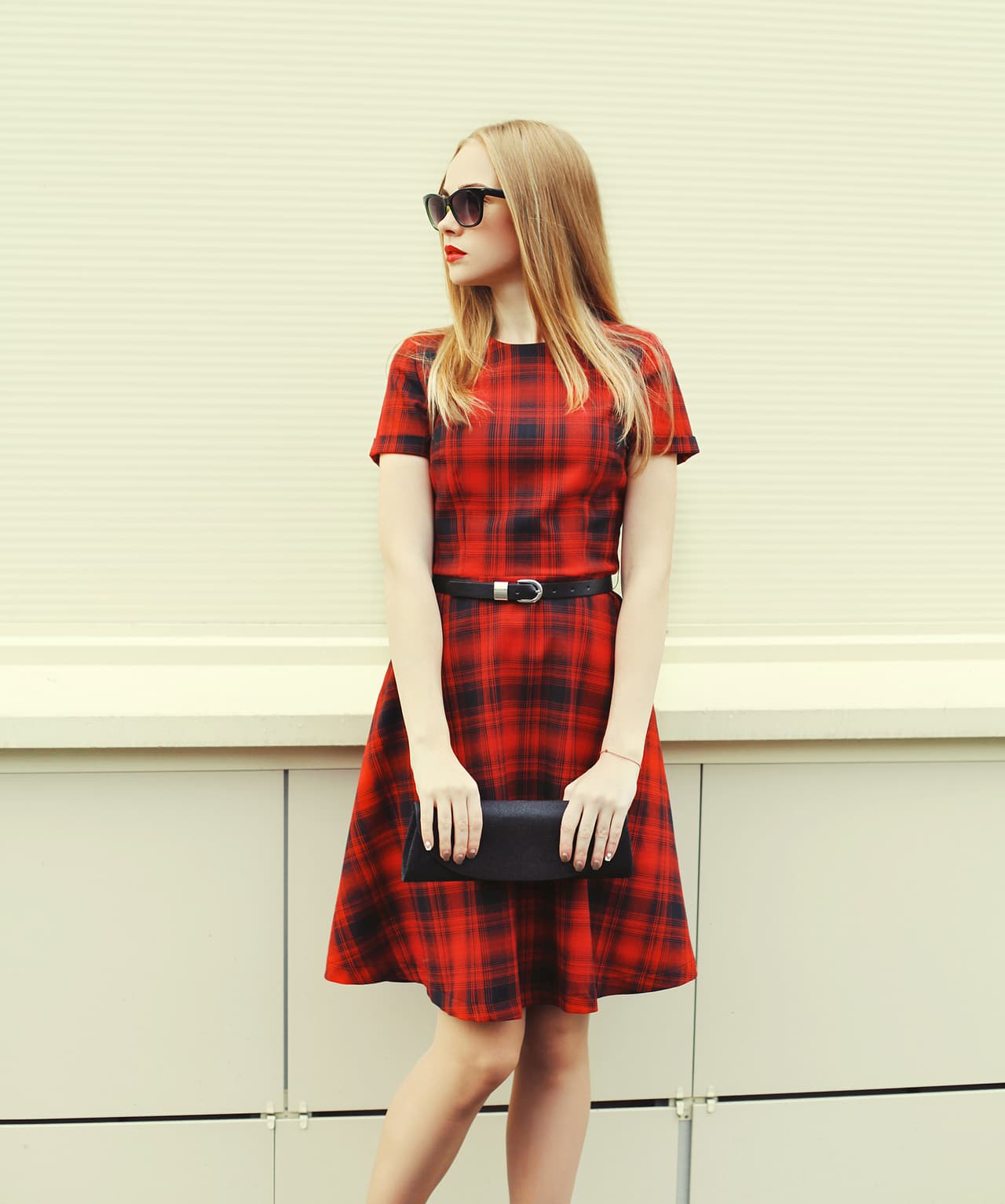 Beautiful blonde woman in red dress, sunglasses with handbag clutch, profile view