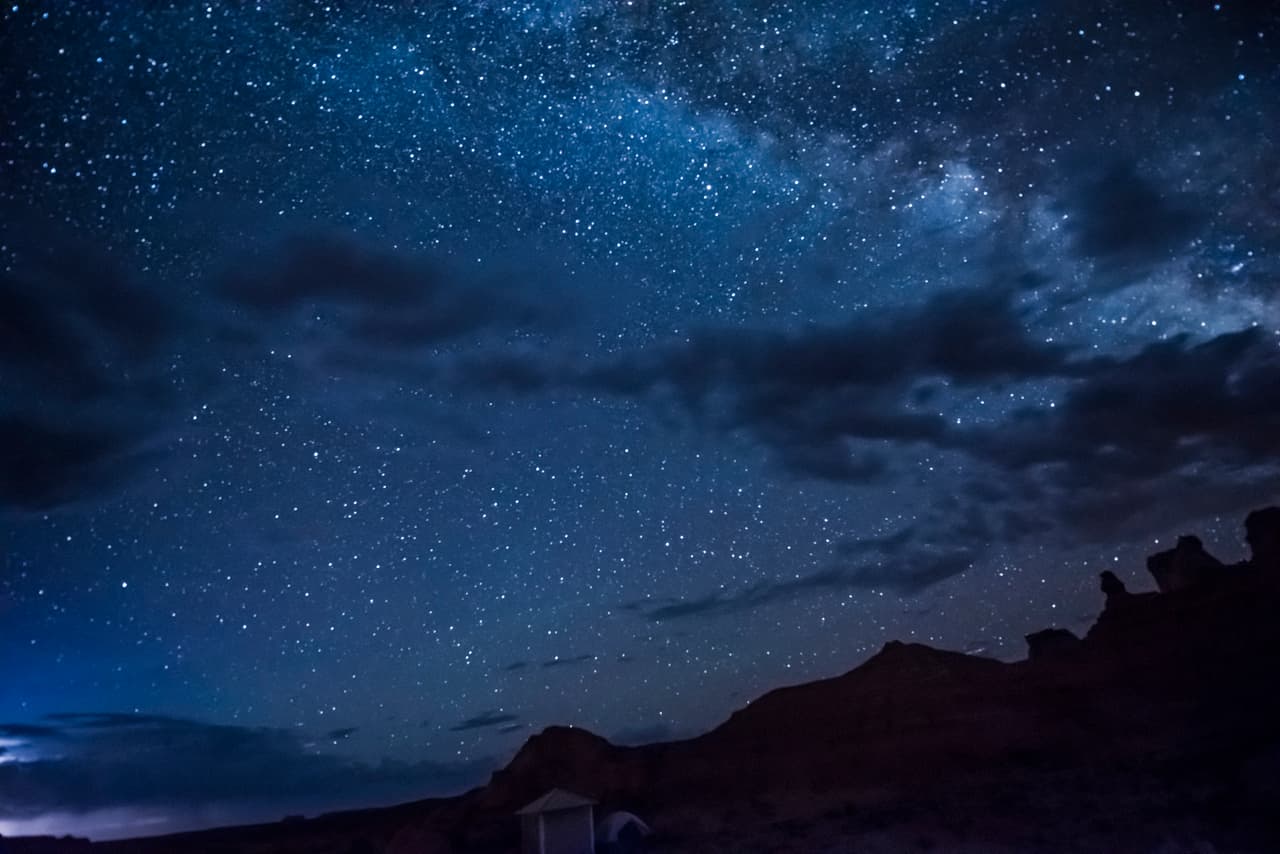 Night sky with milky way, clouds, canyons and campground