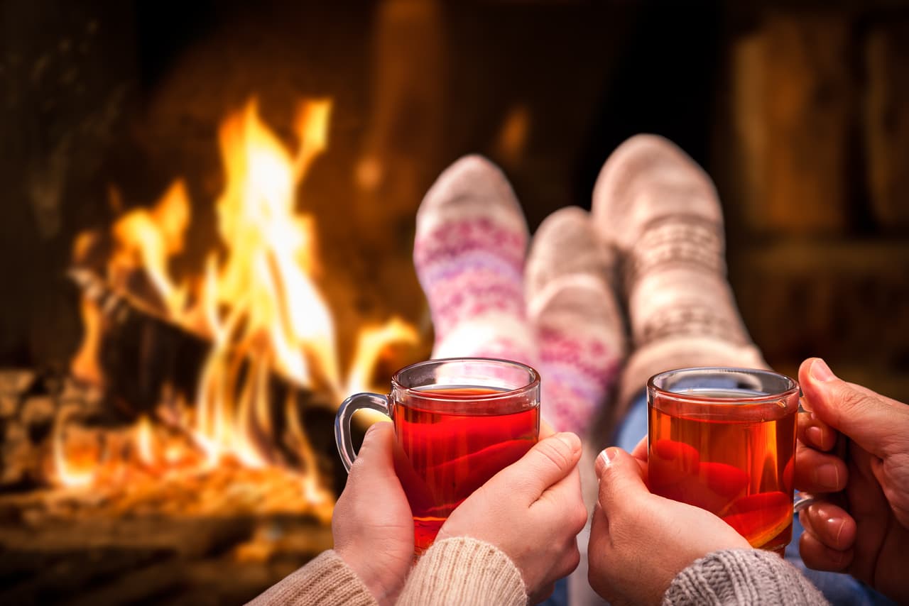 Couple relaxing with mulled wine at romantic fireplace on winter evening