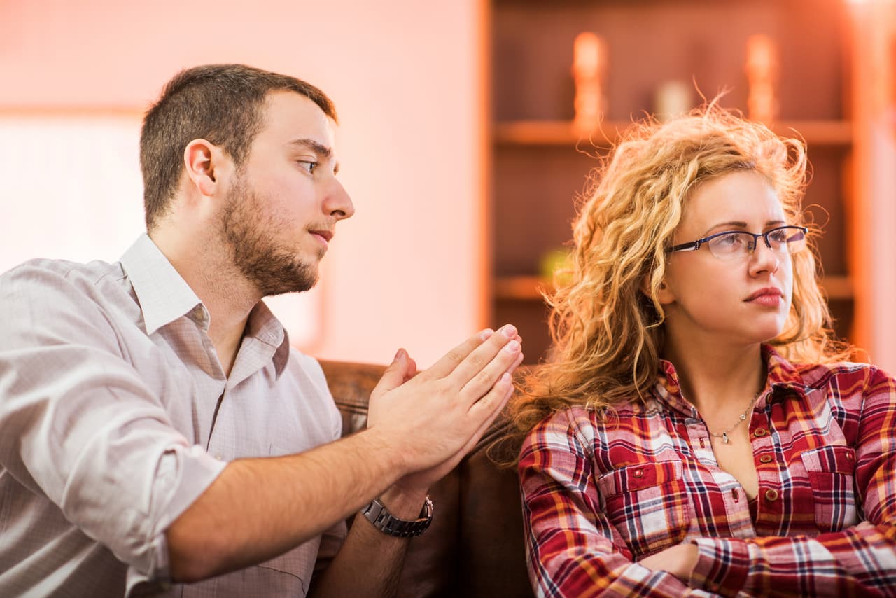 Young man asking his angry girlfriend for forgiveness.