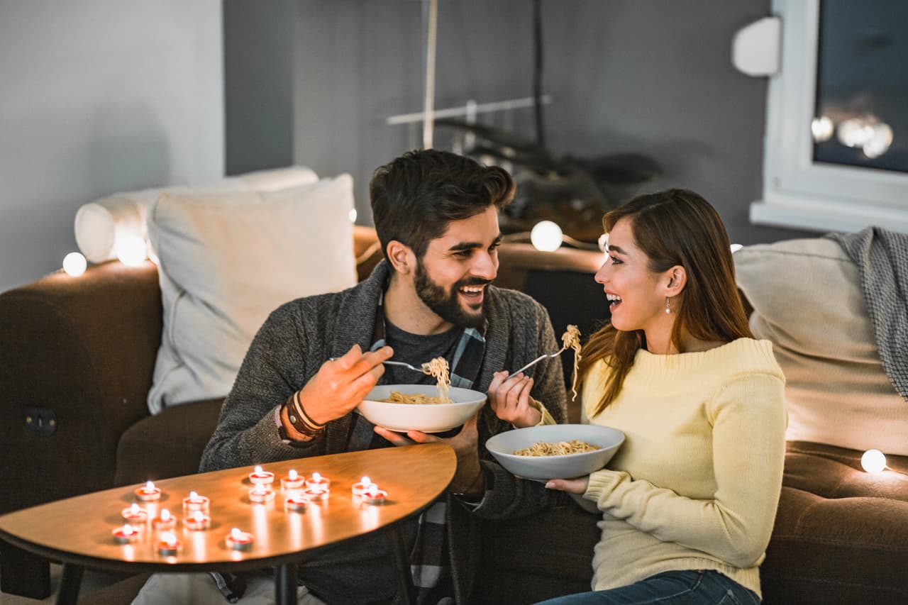 A young couple is at home, they are enjoying their free time and eating dinner