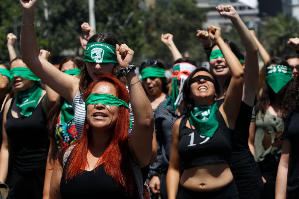 SANTIAGO, CHILE - DECEMBER 06: Demonstrators wearing green handkerchiefs covering their eyes sing and dance in a feminist flash mob performing "Rapist in Your Path" (In Spanish: “Un violador en tu camino”) in protest of violence against women on December 6, 2019 in Santiago, Chile. The song, written by local feminist group Lastesis is becoming an international feminist phenomenon. (Photo by Marcelo Hernandez/Getty Images)