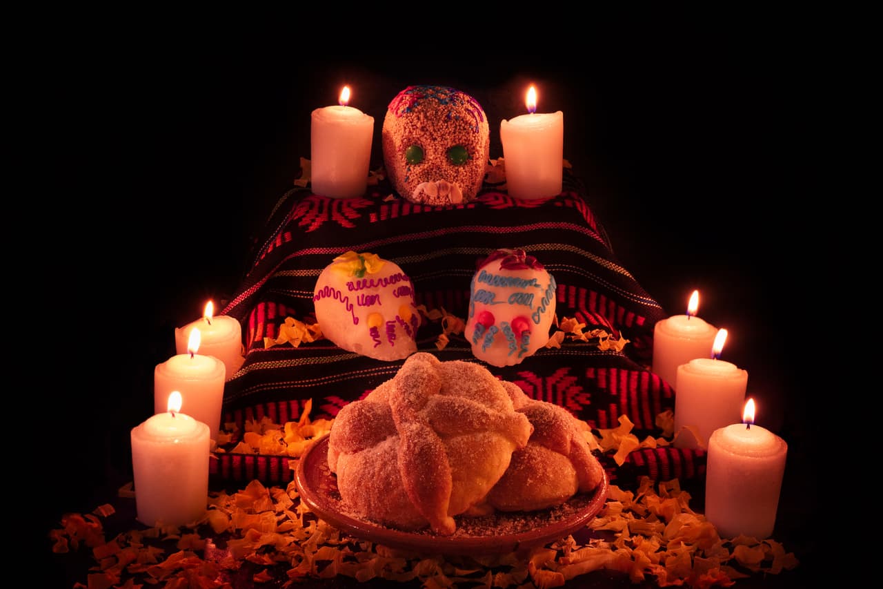 Traditional mexican day of the dead altar with bread and sugar skulls on dark background