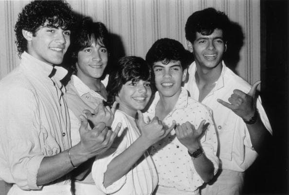 1985: Portrait of the teen pop group Menudo (L-R: Charlie Rivera, Roy Rossello, Ricky Martin, aged thirteen, Ray Acevedo and Robby Rosa) gesturing with their hands while posing in a hallway at the Century Plaza Hotel, Los Angeles, California. (Photo by Fotos International/Getty Images)