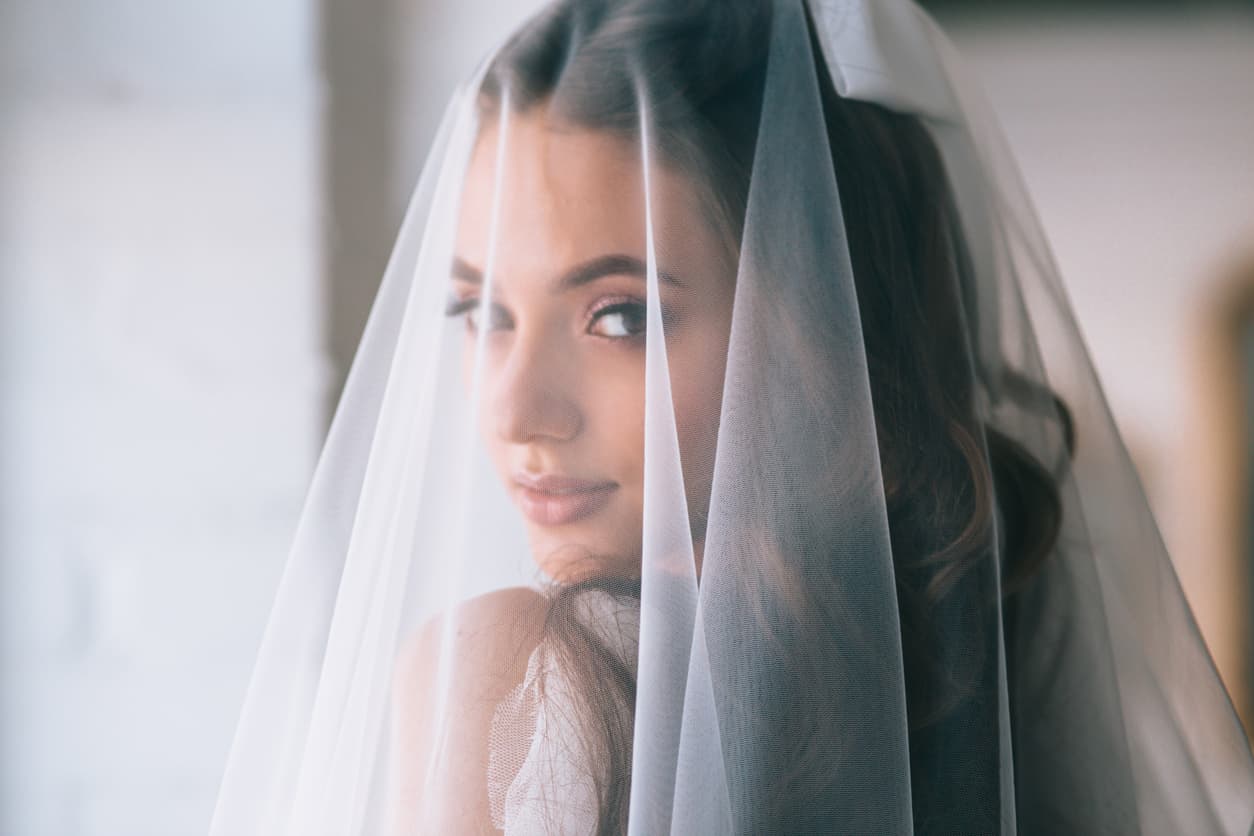 Beautiful bride with fashion wedding hairstyle . Closeup portrait of young gorgeous bride. Wedding. Studio shot.Beautiful bride portrait with veil over her face