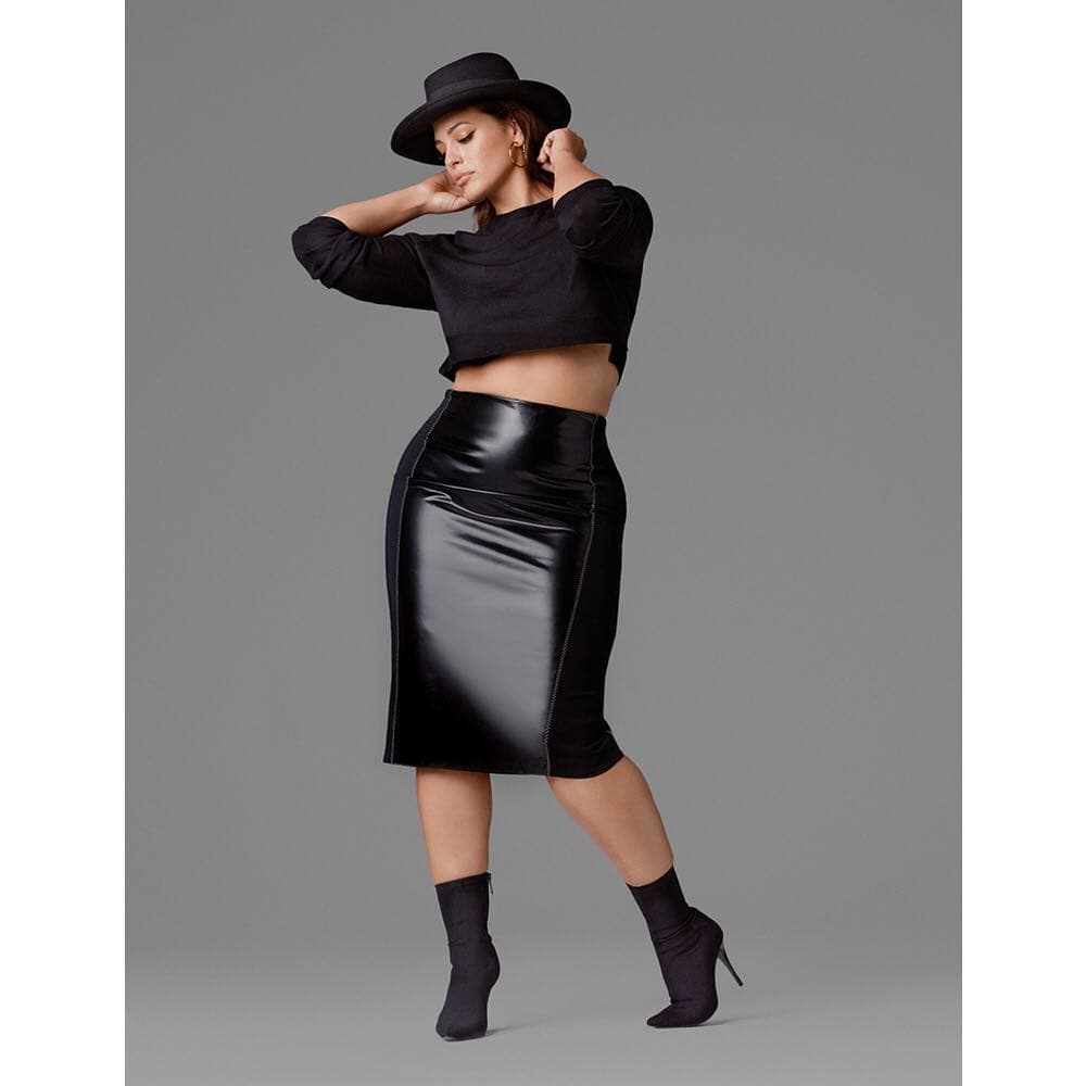 Ashley Graham combina un swetter con la textura brillosa de una falda en piel en corte recto y unos botines aterciopelados