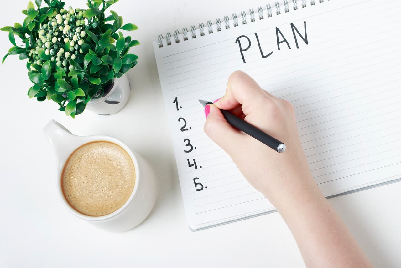 Female hand writes a plan in a notebook, a goal setting concept