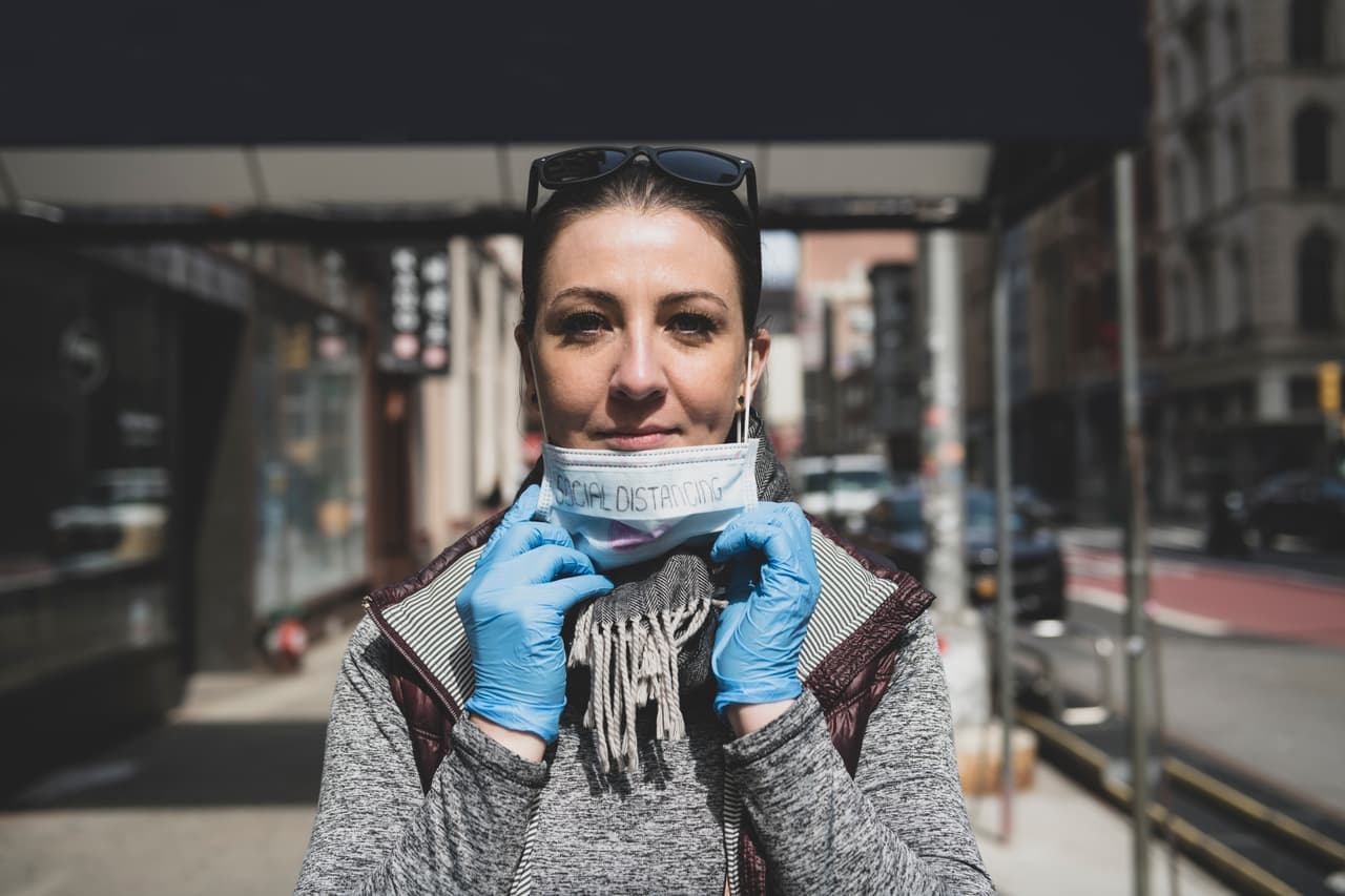 A resident of Lower Manhattan, in light of the growing threat of COVID-19 caused by coronavirus, wears protective gloves and a face mask on which is creatively handwritten "SOCIAL DISTANCING".