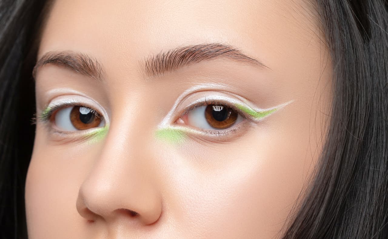 Portrait of a beautiful teenage girl with dark hair, with beautiful creative white and green makeup and healthy clean skin. Makeup and cosmetology concept.