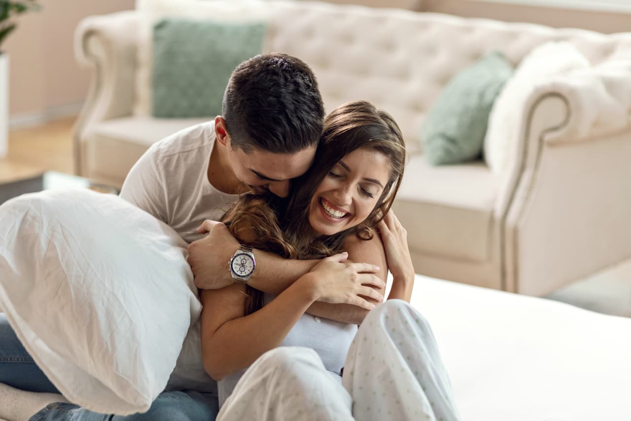 Happy affectionate couple enjoying in their love while embracing in bedroom in the morning.