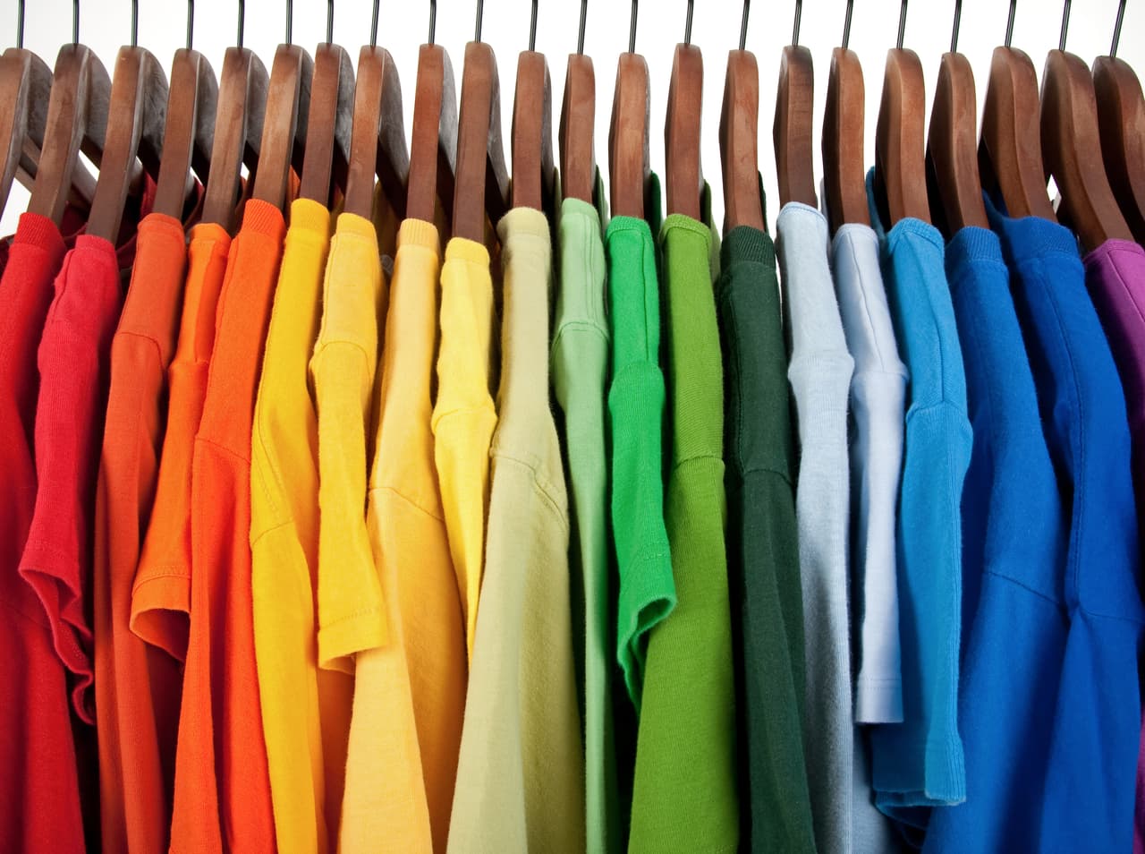Colors of rainbow. Variety of casual clothes on wooden hangers, isolated on white.