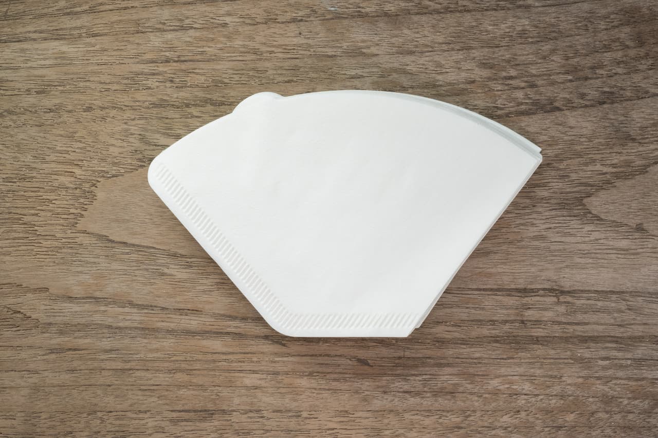 Coffee filter paper cone type on wood background.