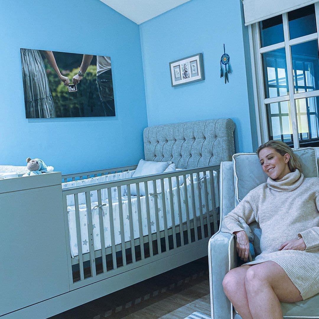Finalmente, la habitación que todos quieren conocer, la del pequeño Liam. Fernanda Castillo compartió recientemente una imagen en la que aparece sentada junto a la cuna. La habitación luce muy elegante con la mezcla de los colores café y azul claro en las paredes y los muebles respectivamente. Y en la pared está un cuadro colgado de una fotografía de Castillo y Hayser sosteniendo la primera imagen de su ultrasonido.