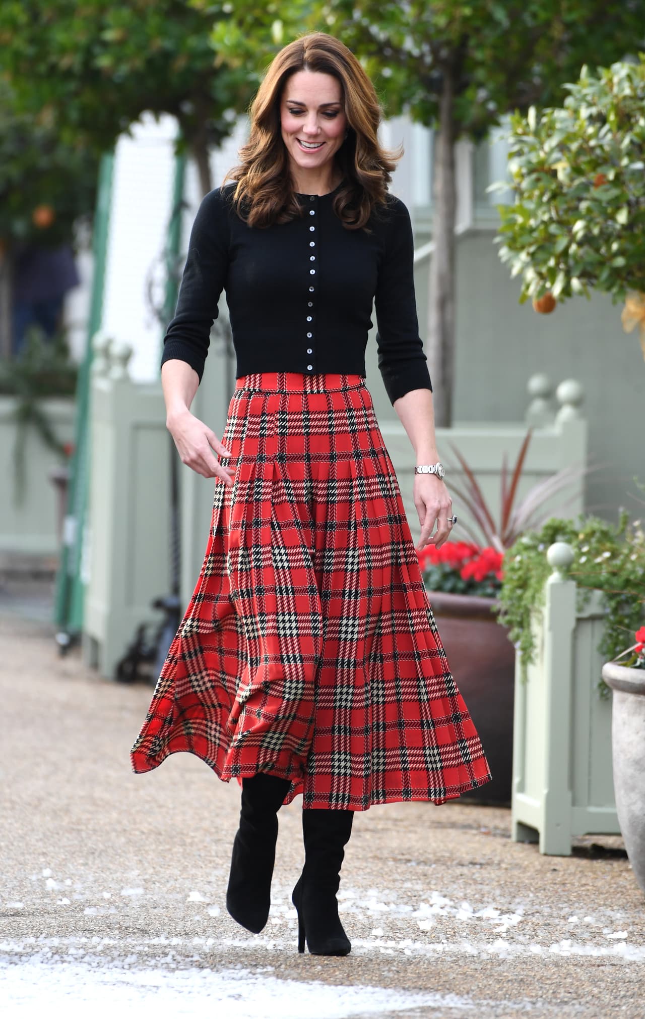2018 - En diciembre de dicho año pudimos ver a Kate radiante en las calles de la capital inglesa con uno de los pocos outfits a dos piezas que ha usado. En éste, la duquesa combinó una falda larga tipo escosesa -también de las pocas prendas que ha usado debajo de la rodilla- un suéter negro con botones y unas botas de tacón. Su cabello, ya más castaño, luce increíble con este look.