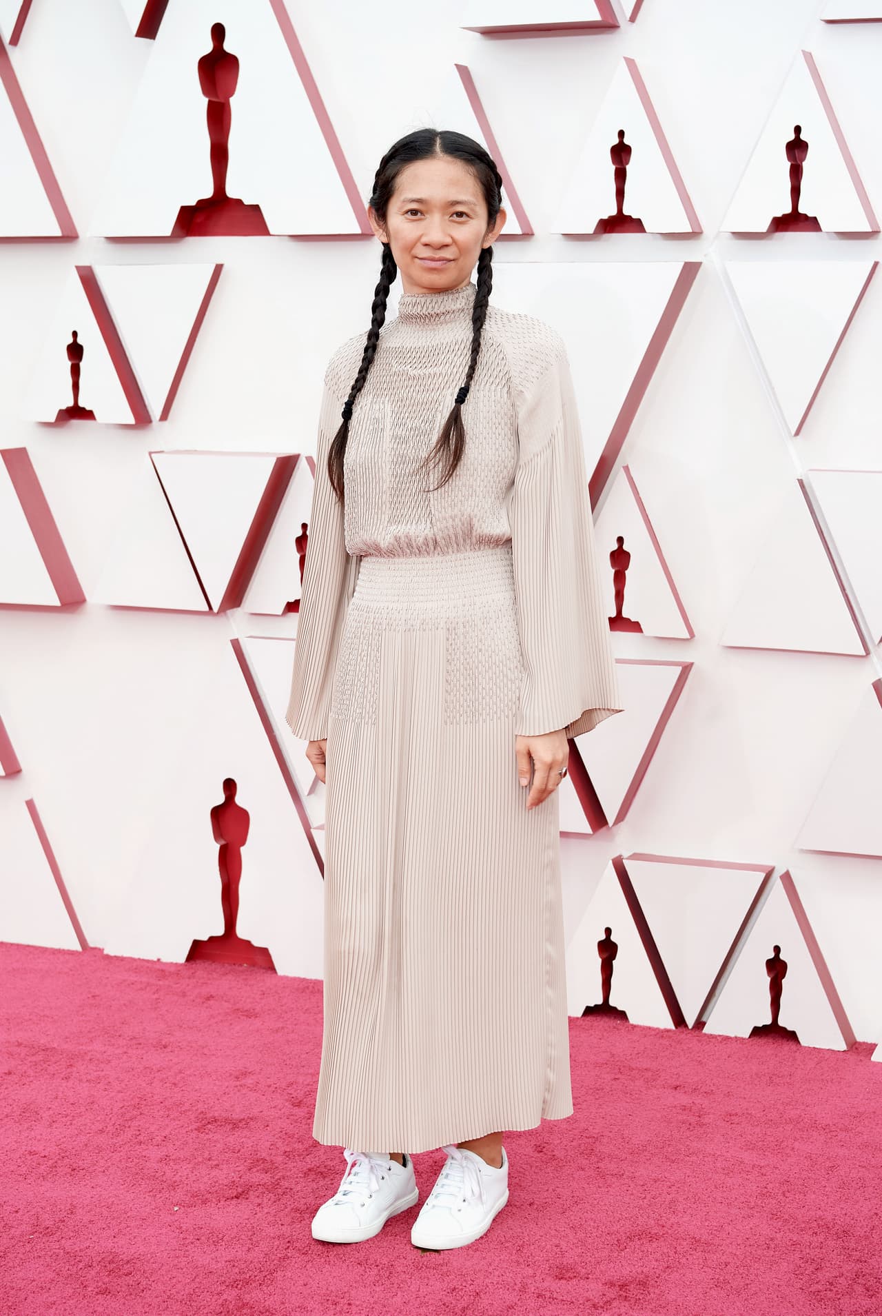 Con la secillez y austeridad que la caracteriza, Chloe Zhao desfiló por la alfombra roja en un vestido indie de color terracota. Lo que más lució de su look fueron los tenis blancos. Ella está nominada en la categoría de mejor dirección por
<i>Nomadland. </i>Si gana, sería la segunda mujer en obtener este premio.