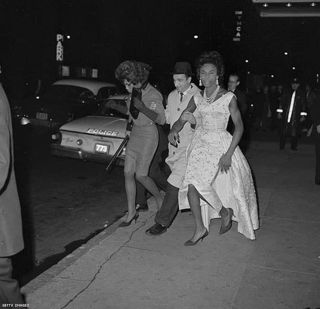 "Policeman Arresting Two Men in Drag", 1962, Bettmann.
<br>
<br>A principios de la década de 1960, el alcalde de Nueva York, Robert F. Wagner, Jr. comenzó una campaña contra la comunidad LGBT+, cerrando los bares gay y atrapando a quienes los frecuentaban. Así que cualquier pareja LGBT que se viera en las calles, era detenida. Esta imagen muestra la manera injusta en que la comunidad fue tratada durante esos años.