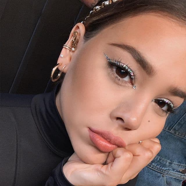 Danna Paola es otra fanática de este estilo, sin embargo, la actriz de “Elite” llevó esta tendencia un poco más lejos y en lugar de usar iluminador en su lagrimal, aplicó una pequeña piedra o sticker holografico.
